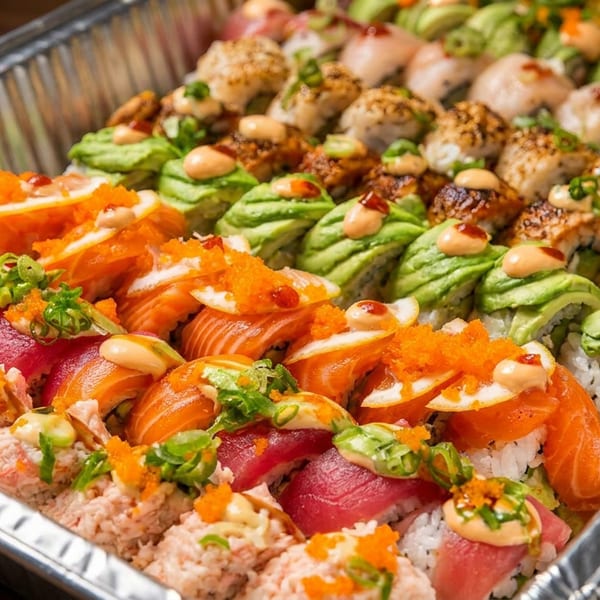 Large sushi platter with various rolls, nigiri, and sashimi in a foil tray.