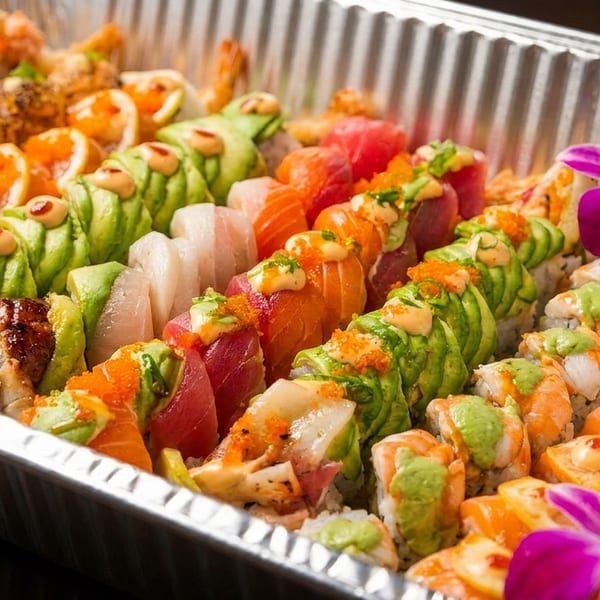 Assorted sushi rolls with avocado, fish, and roe, garnished with orchids and jalapeños.